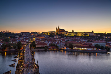 Fototapeta premium View of the crowded Charles Bridge (Karluv most) over Vltava River, Mala Strana district and illuminated Prague (Hradcany) Castle in Prague, Czech Republic, in the evening. Copy space.