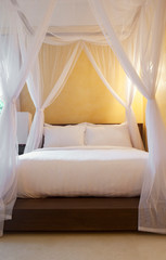 Ko Samui, Thailand - Luxury hotel room bed with a sheer canopy draped from the ceiling.