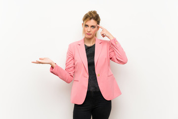 Young blonde woman with pink suit making the gesture of madness putting finger on the head