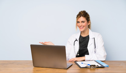 Blonde doctor woman presenting an idea while looking smiling towards