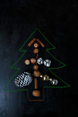 Christmas background with dry orange,white pinecone,green christmas tree balls,mandarins,red apple,ginger sticks,on a black background,flat lay,space for text,space for copy