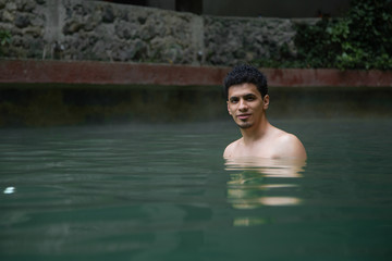 Young Hispanic traveler man enjoying natural hot spring - man relaxing at the spa in Guatemala