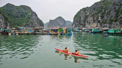 Vietnam, Cat Ba Island, Ha Long Bay. Tourists in kayak and floating village.