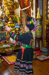 Fototapeta na wymiar Woman in traditional dress performing ceremony in temple, Hanoi, Vietnam