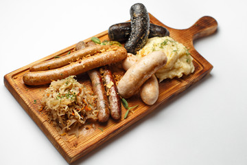 sausages and sausages on a board with mashed potatoes and cabbage