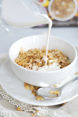 Granola breakfast with milk in a white bowl