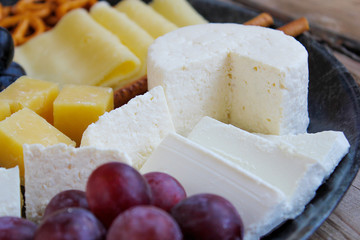 Rustic cheese platter with different cheese and grapes