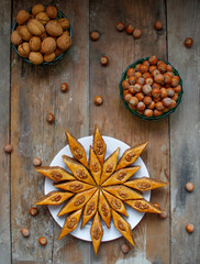 Traditional Azerbaijan holiday Nowruz cookies baklava on white plate on the rustic background with nuts and huzelnuts on green plate ,flat lay