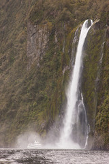 South Pacific, New Zealand, South Island, Fiordland National Park. A tourist boat moves close to Stirling Falls. 