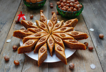 Traditional Azerbaijan holiday Nowruz cookies baklava on white plate on the rustic background with nuts and huzelnuts on green plate ,flat lay