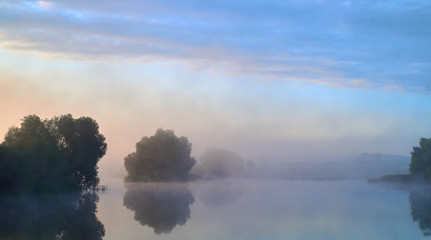 Foggy morning. Dawn outside the city. It will be a warm day. Morning fog on the lake