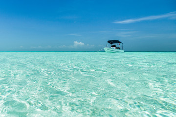 A boat is anchored over a shallow sandbar in clear waters near Staniel Cay, Exuma, Bahamas