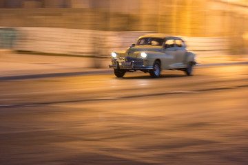 Plakat Cuba, Havana. Vintage Cars at night along the Malecon.