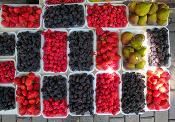 Summer fruits in white plates in bazaar,strawberries,blackberries,raspberries,mulberries