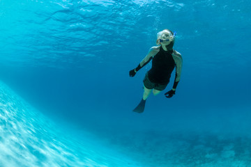 Woman snorkeling beneath the surface in the ultra-clear and blue waters of Staniel Cay, Exuma, Bahamas