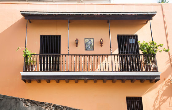 San Juan, Puerto Rico - Two doors with bars on them are set into a peach colored wall with a balcony.