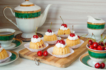 Mini cupcakes on the white wooden table background with tea set and fork