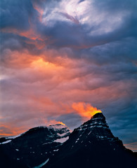 Canada, Alberta, Mt. Chephren. A golden shaft of sunset light ignites a snow plume blowing from the...