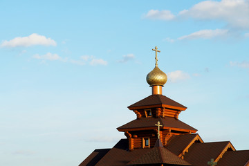 Wooden church with a cross and a golden dome. Brown logs, religion.