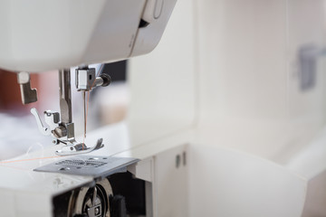 sewing machine with colour thread and needle on a table with blurred background, Tailor's work table, textile or fine cloth making, industrial fabric, home appliances tool.