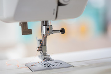sewing machine with colour thread and needle on a table with blurred background, Tailor's work table, textile or fine cloth making, industrial fabric, home appliances tool.