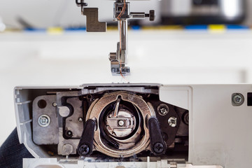 sewing machine with colour thread and needle on a table with blurred background, Tailor's work table, textile or fine cloth making, industrial fabric, home appliances tool.