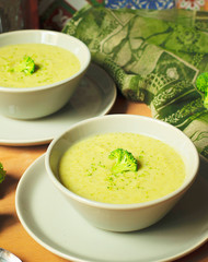 Fresh Broccoli cream soup on two gray ceramic bowl on plate with spoon on marble background,vegetarian food,healthy concept