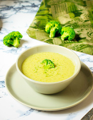 Fresh Broccoli cream soup on two gray ceramic bowl on plate with spoon on marble background,vegetarian food,healthy concept