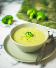 Fresh Broccoli cream soup on two gray ceramic bowl on plate with spoon on marble background,vegetarian food,healthy concept