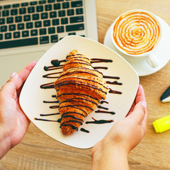 coffe, laptop and croissants to show a business breakfast on the office table in morning