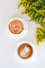Two cups of coffee on the table, latte art with yellow flowers