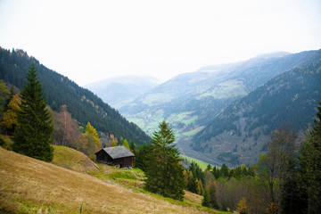 Fototapeta na wymiar Austria - View of a picturesque, green mountains and a valley. A rustic building is viewable on the hillside.
