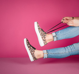 Mujer con tenis con figuras de leopardo sobre fondo de color