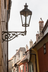 Fototapeta na wymiar Czech Republic, Prague. Golden Lane lamp, chimneys and rooftops at Prague Castle.