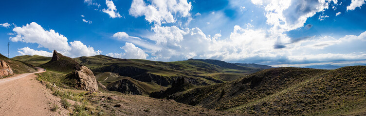 Fototapeta premium Turkey, aerial view of the breathtaking landscape on the dirt and winding road on the plateau around Mount Ararat, Agri Dagi, with rocky peaks, hills, grassland and flowers near the Ishak Pasha Palace