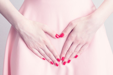 The woman has a stomach ache, the beginning of the menstrual cycle, she touches belly, female hands, close up, cropped image, menstrual period concept, toned