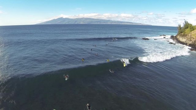 Aerial shot of sufers in Hawaii catching waves, surfing, and wiping out.