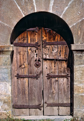 Fototapeta na wymiar Andorra. An ancient old wooden door contrasts against a stone building in Andorra.