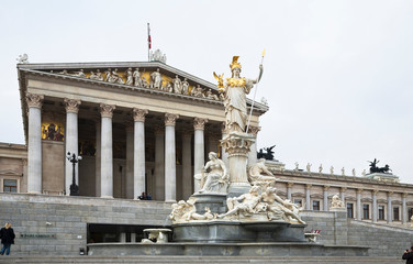 Austria, Vienna. A romanesque statue stands on a dry water feature in front of a building with columns.