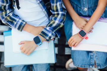Close up view of  two child with smartwatch. Showing hands with smartwatch and colourful wristbands, children tracking gadget with wireless communication.