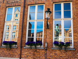 Fototapeta na wymiar Belgium, Brugge, West Flanders, Yan Van Eyck square and statue in reflection in Building Windows