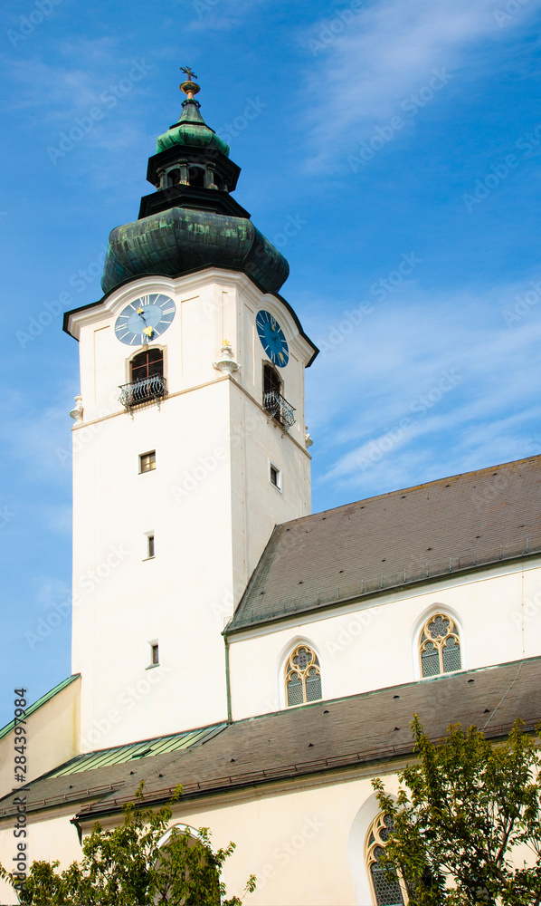 Wall mural Wels, Upper Austria, Austria - Low angle view of a clock and bell tower of an old church.