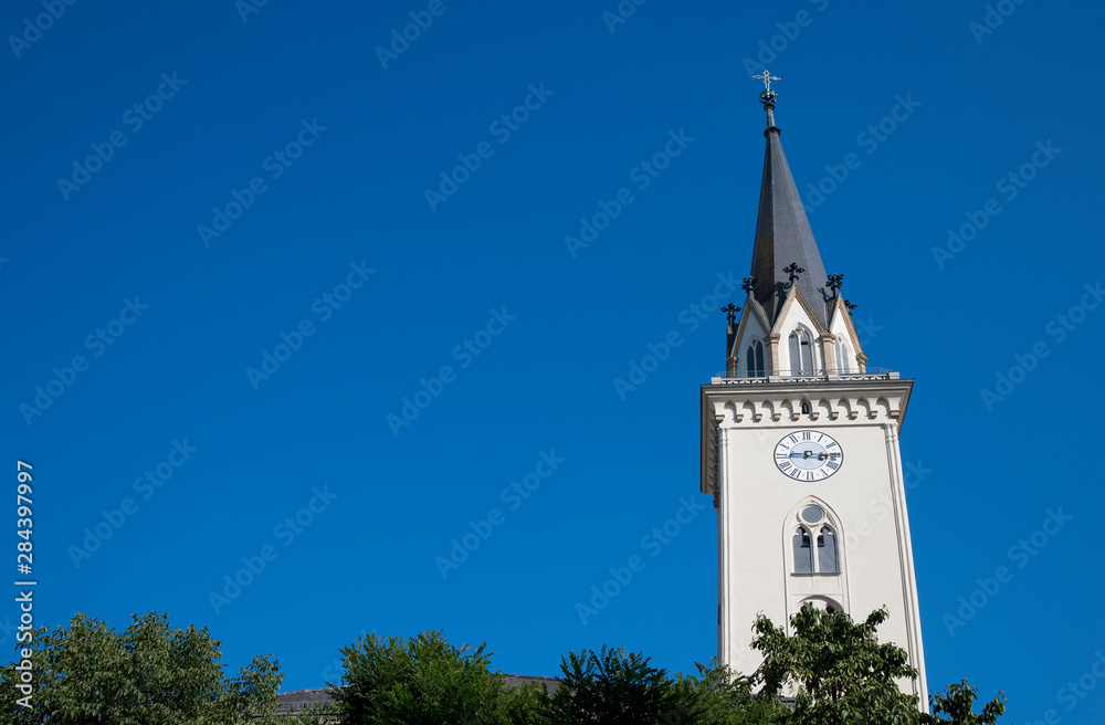 Wall mural Villach, Carinthia, Austria - Low angle view of a white, church steeple with a cross on the top.