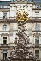Fototapeta na wymiar Austria, Vienna. Low angle view of an ornate religious sculpture in front of an old world building.