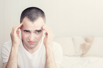 A man in the bedroom, unhappy man sitting on the bed holding his head, toned, the concept of problems in sex