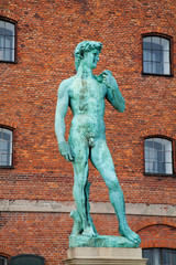 Copenhagen, Denmark - Low angle view of a sculpture of David. A brick building is viewable in the background.