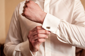 A groom fastening a cuff-link before getting married