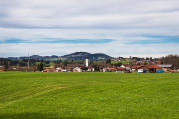 Fototapeta na wymiar Village across a field with a typical Bavarian church nestled in the hills in Germany