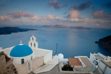 Fototapeta na wymiar Greece, Santorini. Bell tower and blue domes of church in village of Firostefani