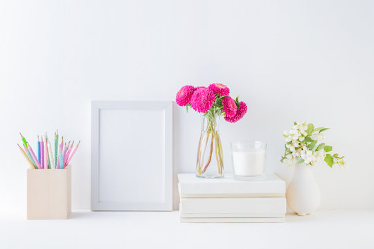 Home interior with decor elements. White frame, pink flowers in a vase, interior decoration